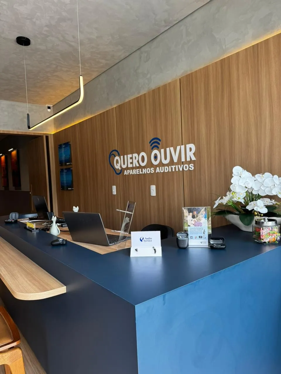 Recepção da unidade de Palmas, com balcão azul e o logo na parede de madeira